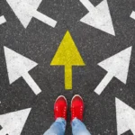 Person standing on the road to future life with many direction sign point in different ways and only yellow one. Decision making is very hard, but you have a choice and right way