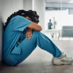 Doctor, depression and stress with black woman on floor for patient loss, surgery fail or death in hospital. Mental health, sad or anxiety for healthcare worker nurse in medical community clinic