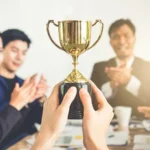 Businessman show thumbs up with trophy, reward, winner, champion and successful for business