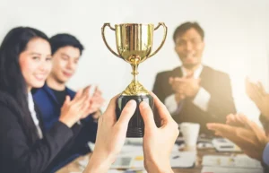 Businessman show thumbs up with trophy, reward, winner, champion and successful for business