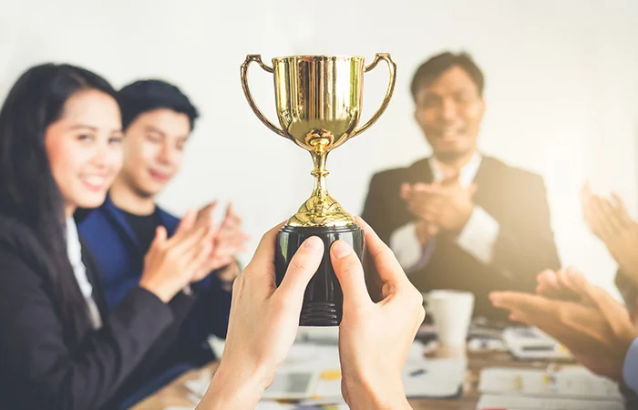 Businessman show thumbs up with trophy, reward, winner, champion and successful for business