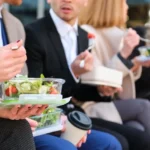 Unrecognizable businesspeople on lunch break talking while eating salad.