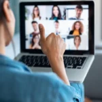Business woman making video call and showing thumb up to laptop